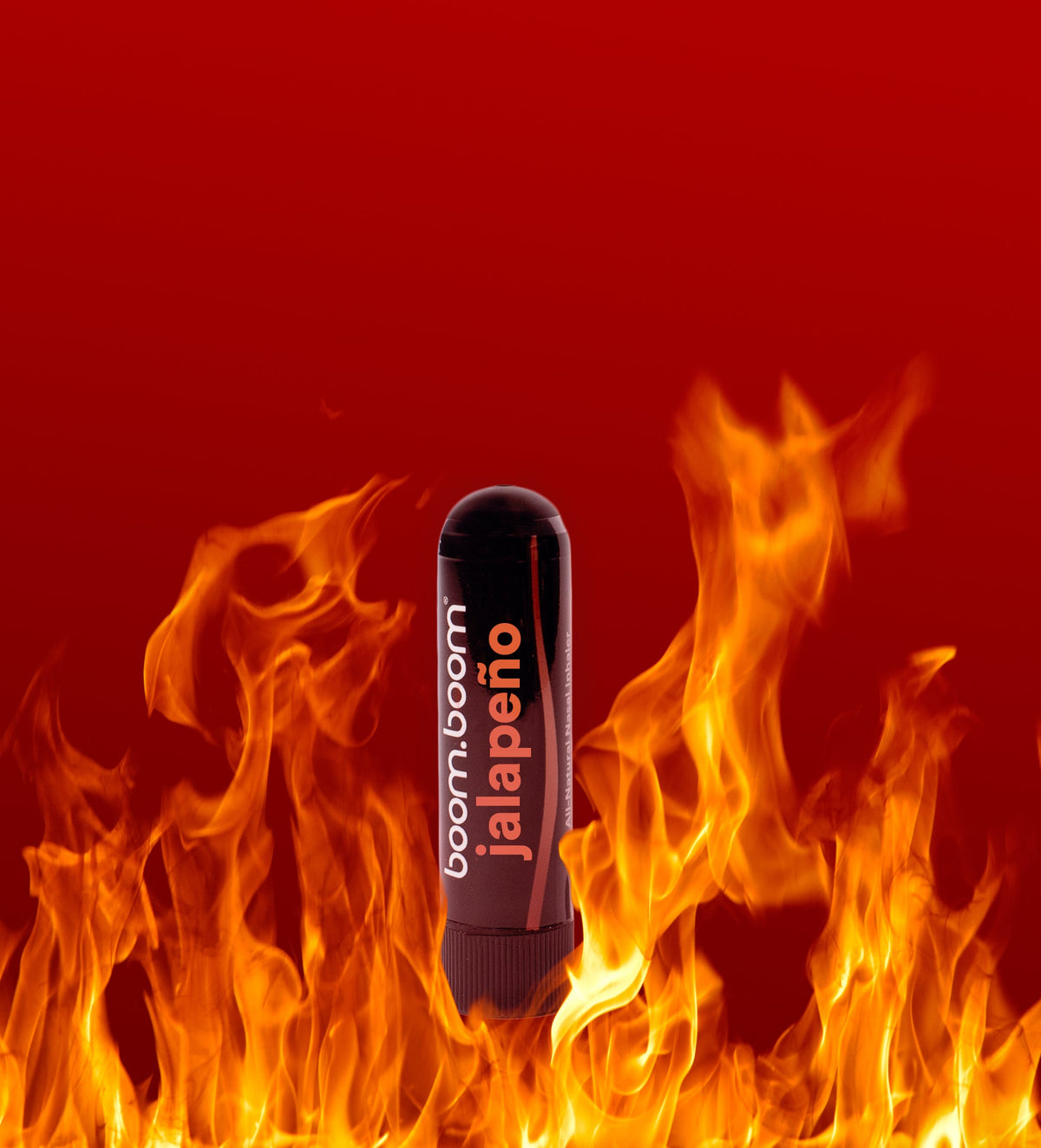 Front view of jalapeno nasal stick showcasing black tube packaging with jalapeno label against red background with flames (april fool's day joke product)