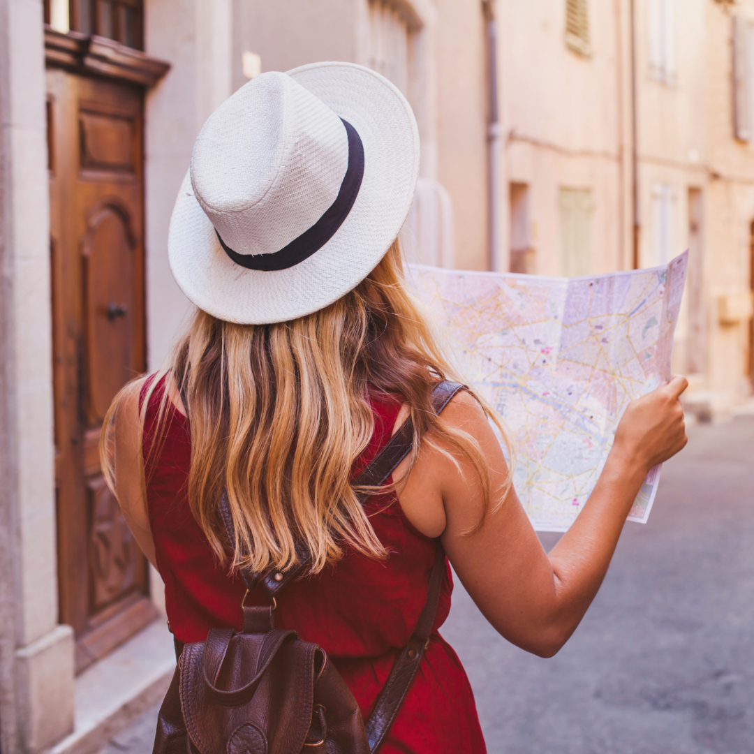 Woman in a straw hat holding a map while exploring a sunlit narrow street