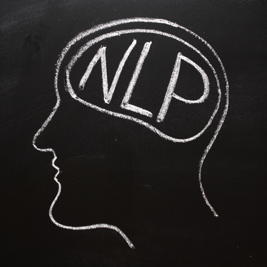 Chalk drawing of a human head profile on a blackboard with NLP written inside the brain area