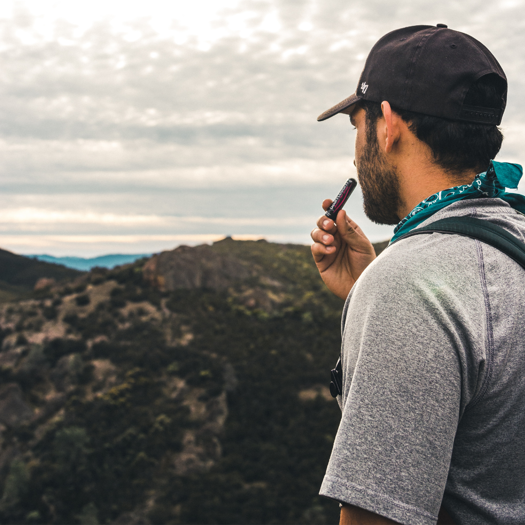 Hiker inhaling a pocket-sized nasal stick at a mountain overlook