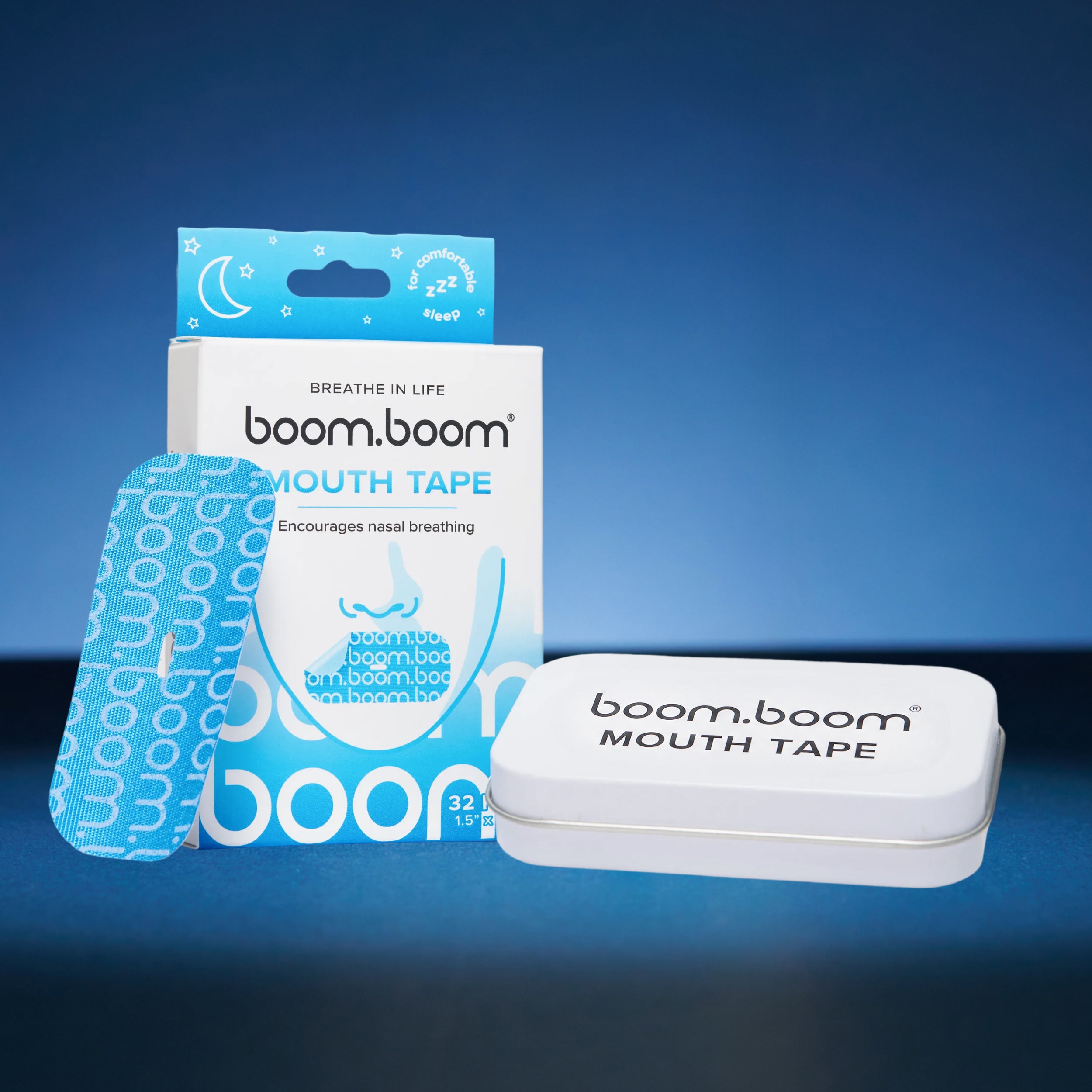 Front view of Mouth Tape tin container with BoomBoom branding, next to product box and patterned mouth tape on blue background